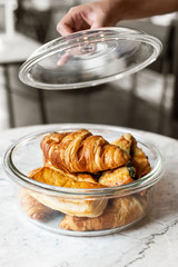 Croissant in glass dessert jar on marble table.