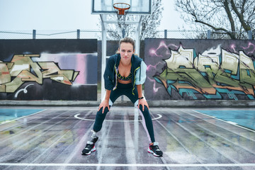 Be stronger. Young healthy disabled woman is standing on stadium and looking at camera while doing...