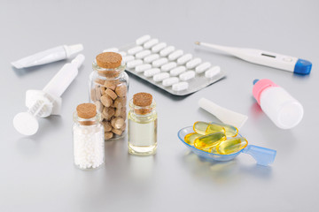 various medical products, natural supplement and thermometer on gray background