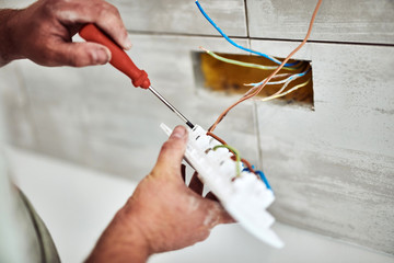 Electrician repairing / fixing wires in the wall.