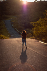 young woman wal on road in sunset