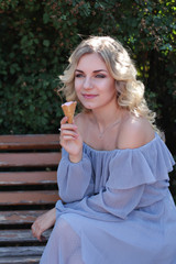 The girl in a beautiful dress eats ice cream in sunny weather