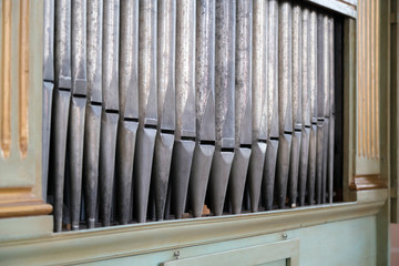 Old, silver organ pipes in a church used for playing sacred music. Many air pipes, sound tubes in...