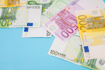 Stack of Euro bank notes on blue background in the studio with space for text