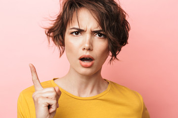 Displeased beautiful woman posing isolated over pink wall background.