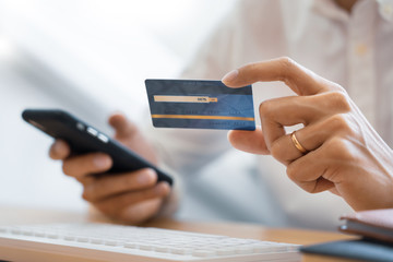 Hand of man in casual shirt paying with credit card and using smart phone for online shopping making orders via the Internet using mobile bank application, Online payment.