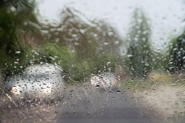 Rain drops on front car window, driving in heavy rain. Pouring rain, water drops on window. Concept of windshield not working, dangerous driving conditions