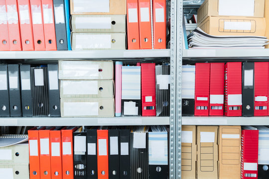 Colourful blank blind folders with files in the shelf. Archival, stacks of documents at the office or library. Physical document storage units