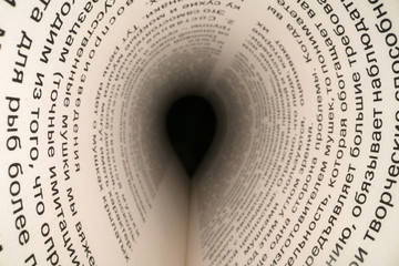 Inside the book concept. Latin letters and words on an tunnel shaped, perspective book page with black dramatic light. Education, knowledge concept