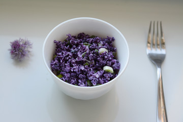 Obraz na płótnie Canvas Dietary red cabbage salad in a white plate and purple flower on white background