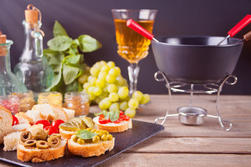 Italian bruschetta in assortment on the plate, glasses with white wine, grapes, fondue. Party or dinner concept.