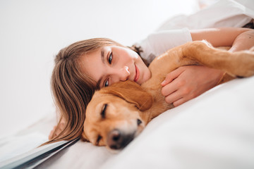 Girl embracing dog on the bed