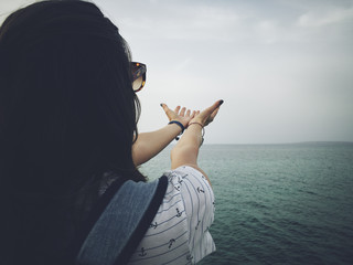 Woman with praying arms on a sea shore.