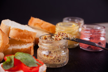 Set of mustard with buns on black plate.