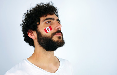 Sport fan head high and feeling proud when listening to the anthem of his country. Man with the flag of Peru makeup on his face and white t-shirt. - Powered by Adobe