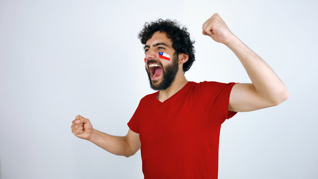 Sport fan screaming for the triumph of his team. Man with the flag of Chile makeup on his face and red t-shirt. - Powered by Adobe