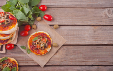 Homemade mini pizza on the wooden background.