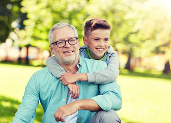 family, generation, relations and people concept - happy grandfather and grandson hugging at summer park