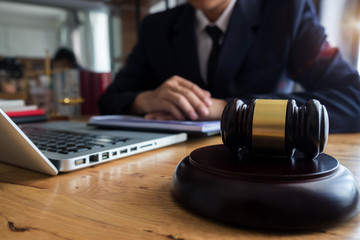 justice and law concept.Male judge in a courtroom the gavel,working with digital tablet computer on wood table.