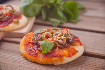 Homemade mini pizza on the wooden background.