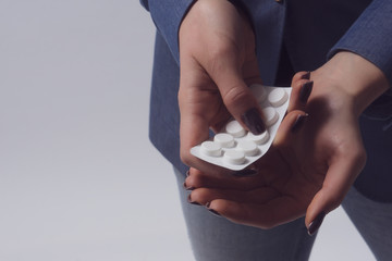 Woman taking out a pill from blister. Closeup on hands and pills. Copy space. Self-medication.