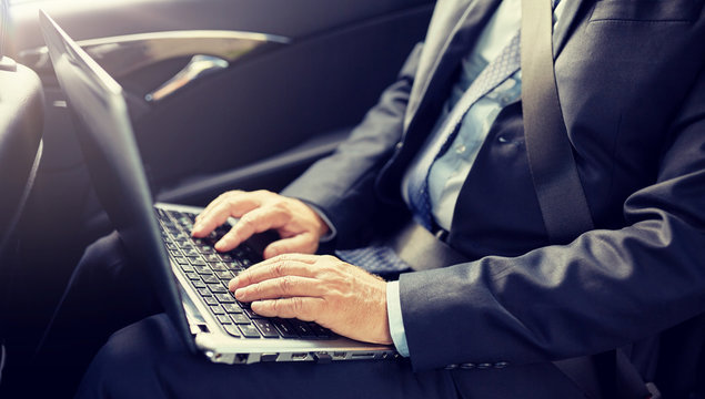 transport, business trip, technology and people concept - senior businessman with laptop computer driving on car back seat