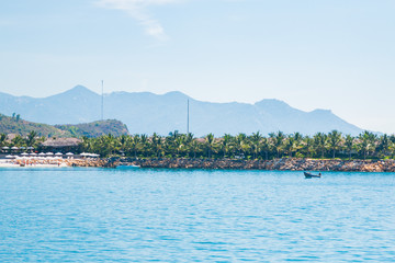 Fototapeta premium landscape, view from the sea, white beach, palm trees, mountains, boat, plane in the sky, Vietnam. five star hotel.