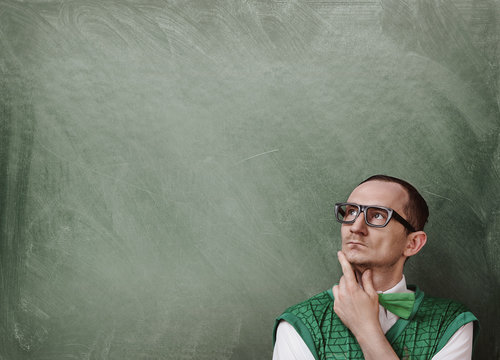 Funny retro nerd thinking over the chalkboard background with copy space