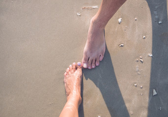 one male and one female feet on the sand
