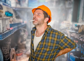 exhausted construction worker or repair man wearing builder helmet complaining suffering pain in...