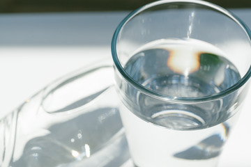 Glass of water with a bottle on table