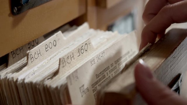 Girl student looking for a book in the library card catalog 