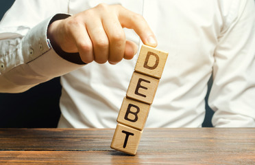 Businessman removes wooden blocks with the word Debt. Debt relief or cancellation is the partial or...