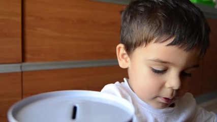 cute two years old saving money, putting coins in metal bank