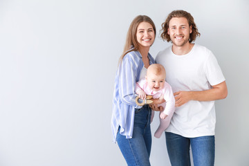 Happy parents with cute little baby on light background