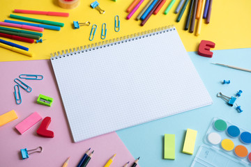 Group School supplies around a notepad on color background.