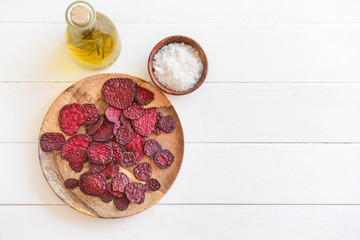 Plate with tasty beet chips on table