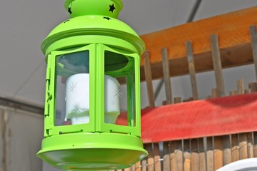 Outdoor green lantern hung with a white candle inside.