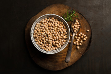 Garbanzos secos con cuenco sobre fondo de madera rústica vista desde arriba