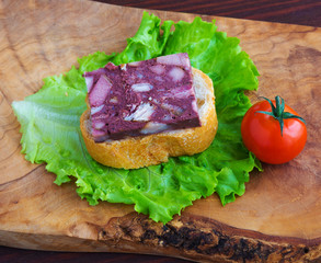 Sandwich with black pudding with a leaf of lettuce and yellow and red tomatoes are on the olive...