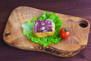 Sandwich with black pudding with a leaf of lettuce and yellow and red tomatoes are on the olive...