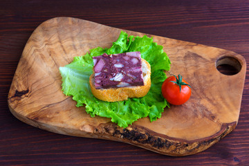 Sandwich with black pudding with a leaf of lettuce and yellow and red tomatoes are on the olive...