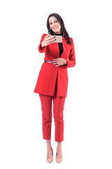 Happy smiling business woman in red suit taking selfie photo looking at phone camera. Full body isolated on white background.