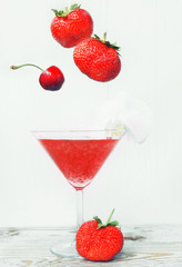 Refreshing healthy drink with chia seedsand falling strawberries and cherries. The atmosphere of summer and relaxation. Proper nutrition.