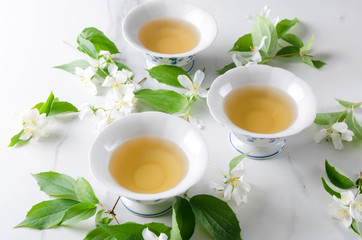 Tea time.Cups of hot green tea and jasmine branches on the white table