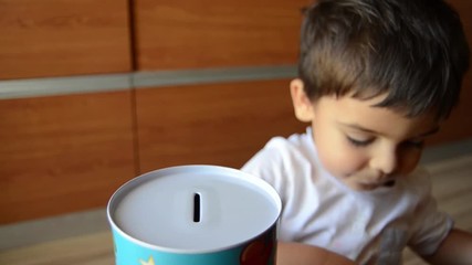 cute two years old saving money, putting coins in metal bank