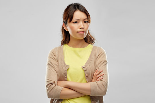 negative emotions, expressions and people concept - displeased asian woman with crossed arms over grey background