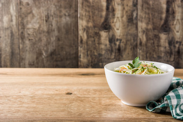 Coleslaw salad in white bowl on wooden table
