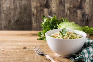 Coleslaw salad in white bowl on wooden table. Copyspace