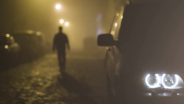 The man walking on the foggy street. evening night time